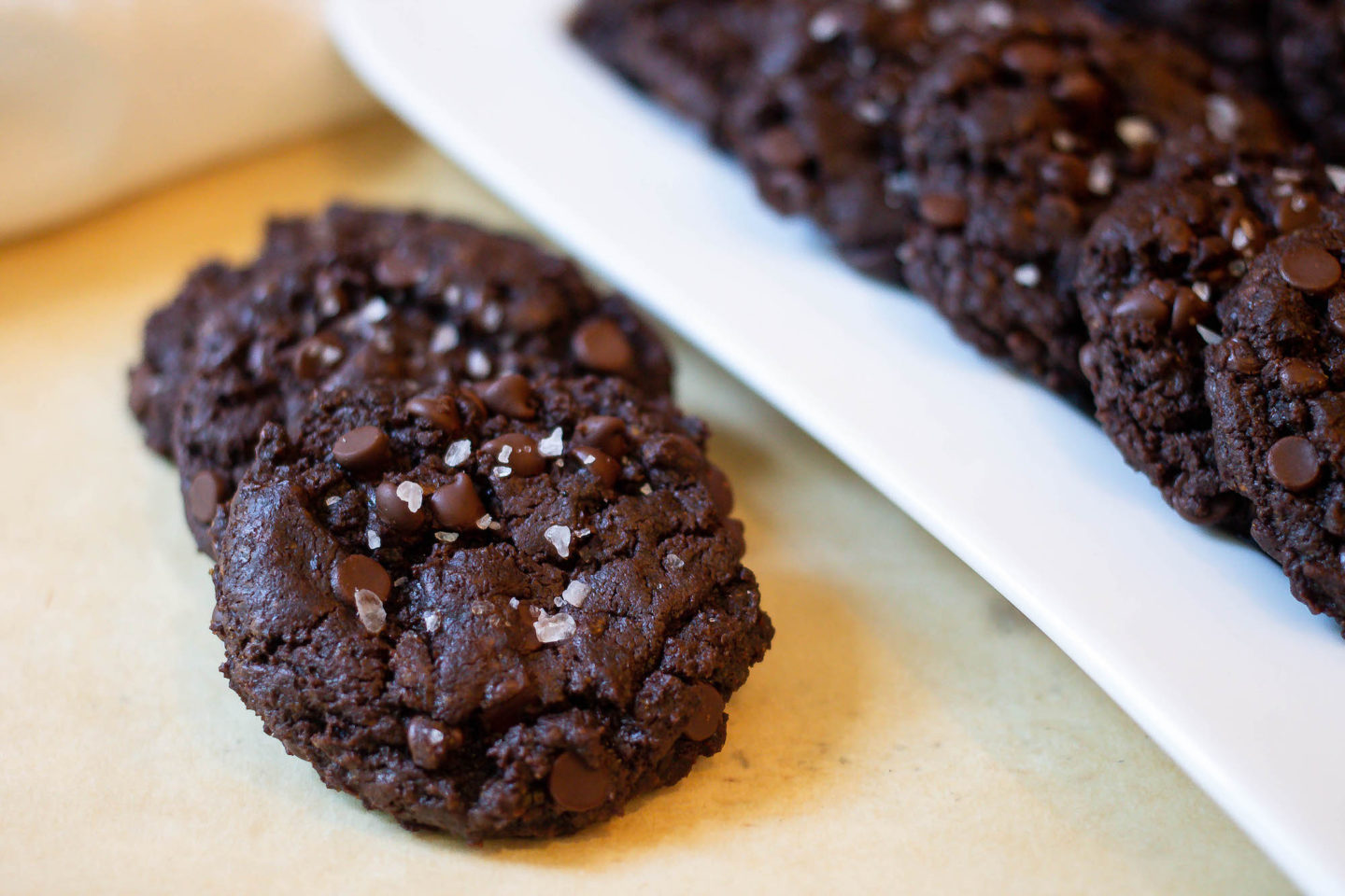 Close up of Vegan Double Chocolate Chip Cookies with more on a white tray in the background