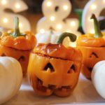 Stuffed orange peppers and cut to look like Jack-O-Lantern with two white pumpkins on either side of the pepper