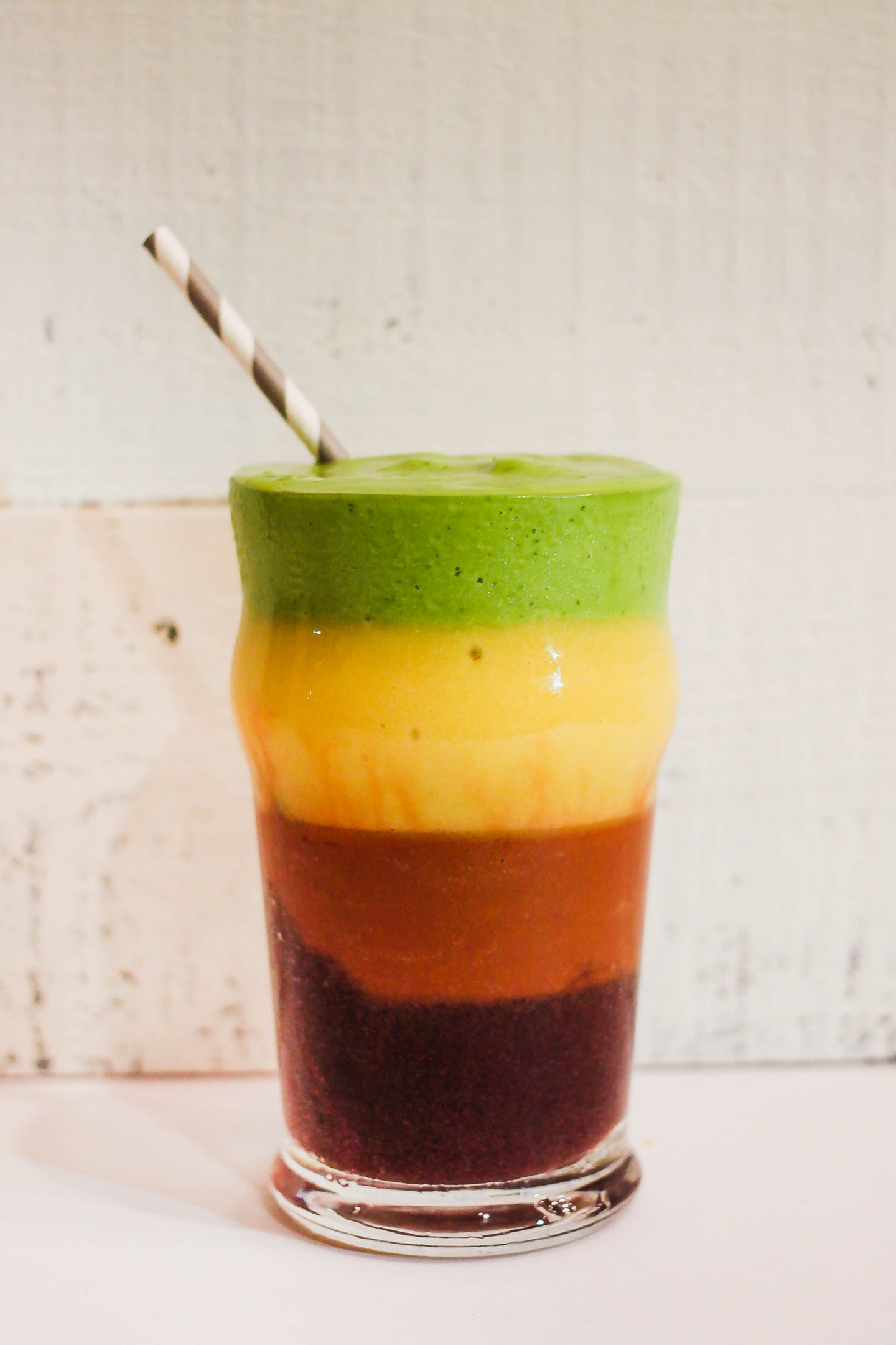 4 Detox Smoothies Layered in one glass with straw