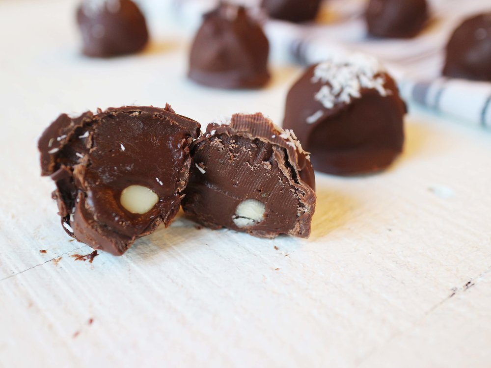 Paleo and Vegan Chocolate Truffles, one cut open in half with other whole ones surrounding it