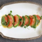 Pink Grapefruit and Avocado Salad on a white plate drizzled with vinaigrette and garnished with microgreens