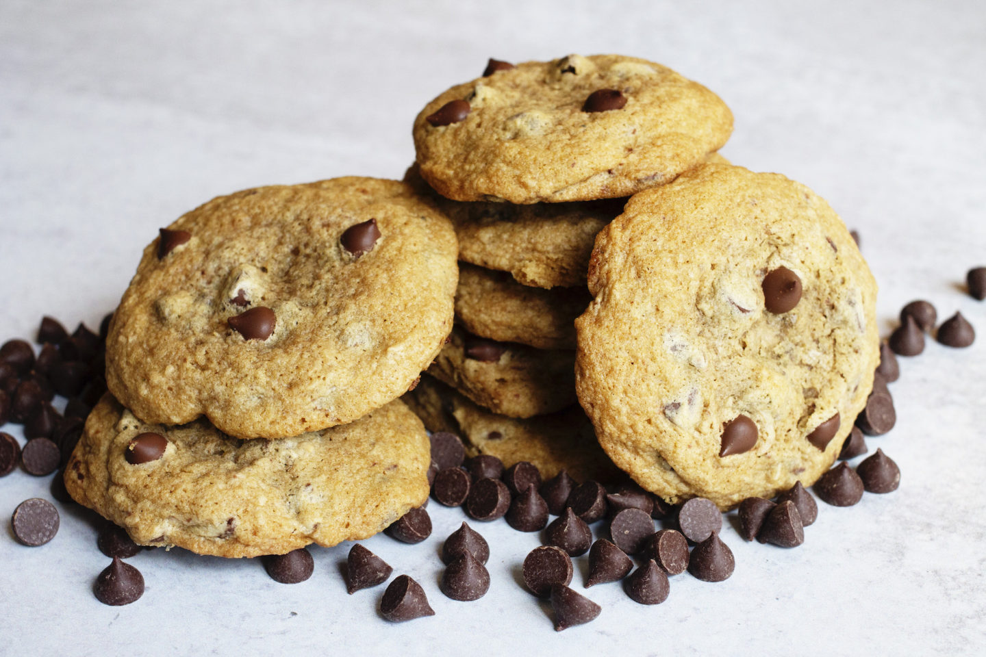 Stacks of gluten-free chocolate chip cookies with chocolate chips scattered around