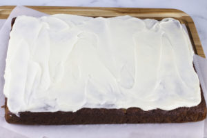 baked iced carrot cake on a cutting board