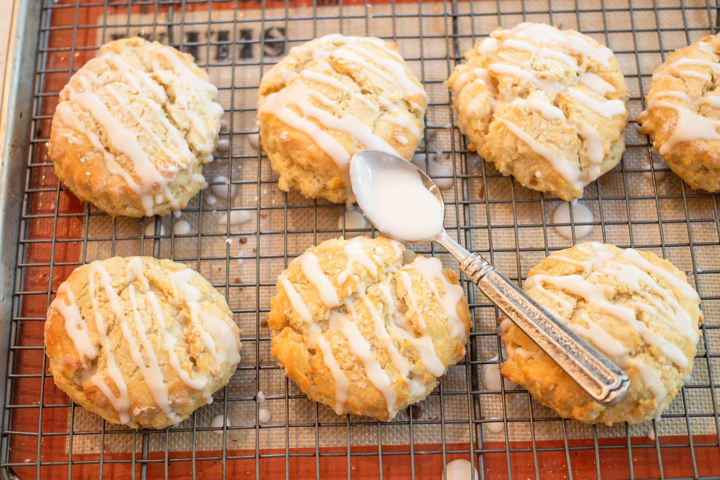 baked gluten free scones on drying rack with glaze and spoon
