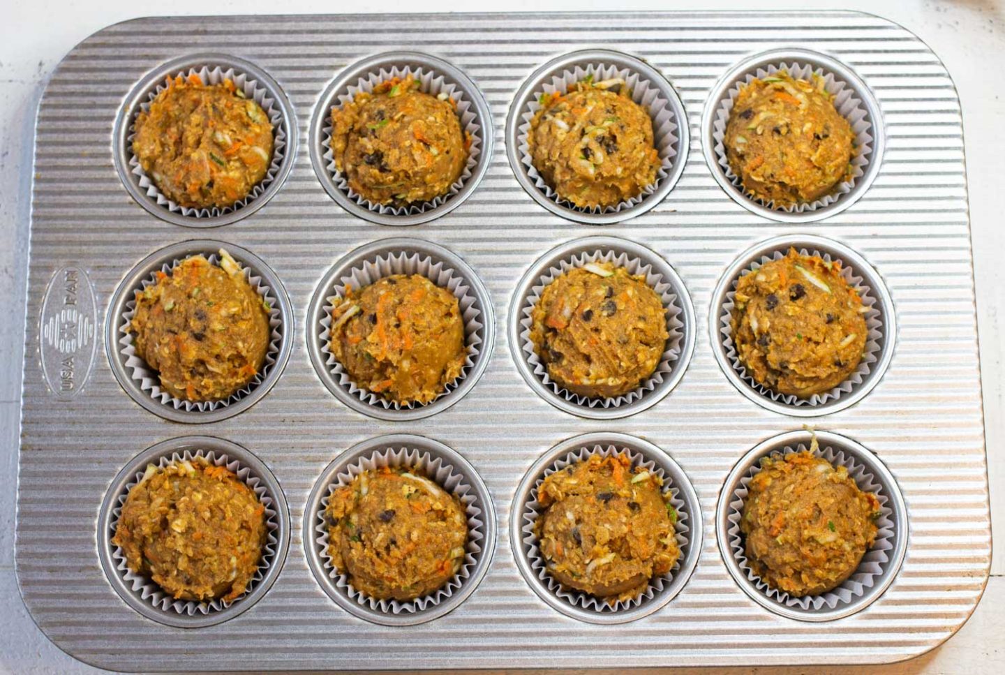 Pumpkin Protein Muffins in a muffin pan with liners
