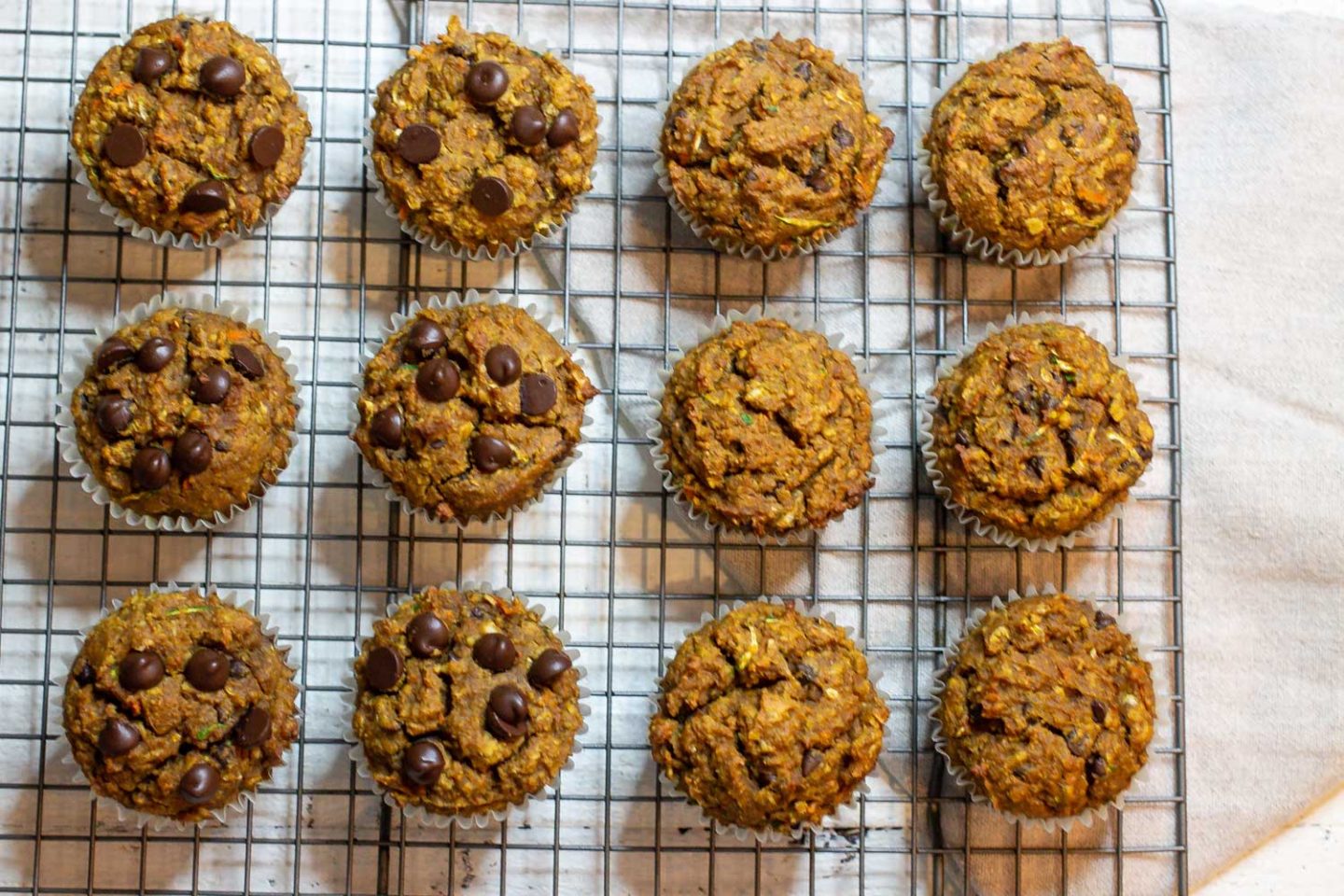 Pumpkin12 Protein Muffins cooling on a cooling rack, 6 with chocolate chips on top, 6 without