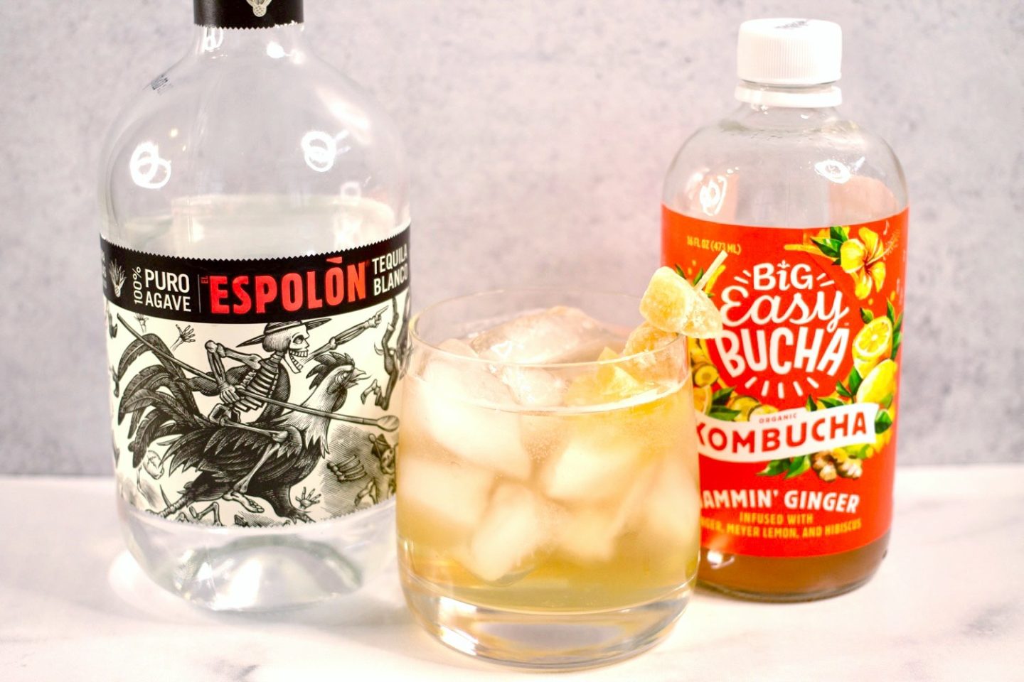 Mexican Mule Ingredients, bottle of Espolòn tequila and bottle of Big Easy Buchcha with the cocktail in between