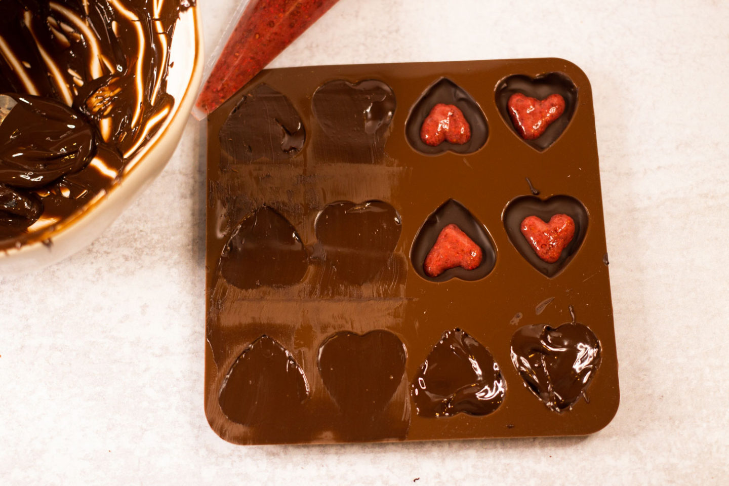 Heart shaped chocolate mold, some with strawberry filling and some completely finished and smoothed over